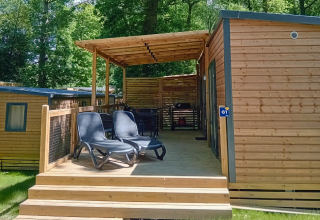 Houten lodge met overdekt terras en ligstoelen bij Homeflower Premium, Flower Camping La Chênaie, Frankrijk.