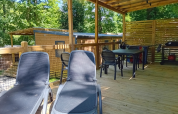 Overdekt houten terras met ligstoelen en eettafel bij Homeflower Premium op Flower Camping La Chênaie, Frankrijk.