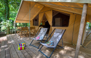 Safari-Zelt mit Holzterrasse, Liegestühlen und Sitzbereich bei Flower Camping La Sagne in Frankreich.