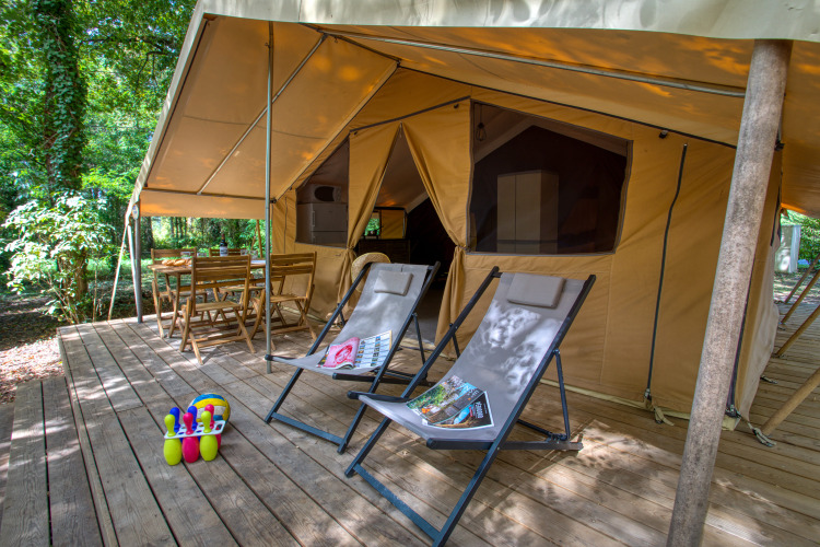Tenda safari su terrazza in legno con sdraio e tavolo a Flower Camping La Sagne, Francia.