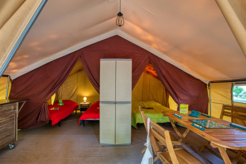 Interior de la Tente Safari Confort en Flower Camping La Sagne, Francia, con camas y mesa de madera.