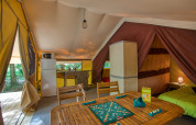 Innenraum des Tente Safari Confort im Flower Camping La Sagne, Frankreich, mit Küche und Spieltisch.