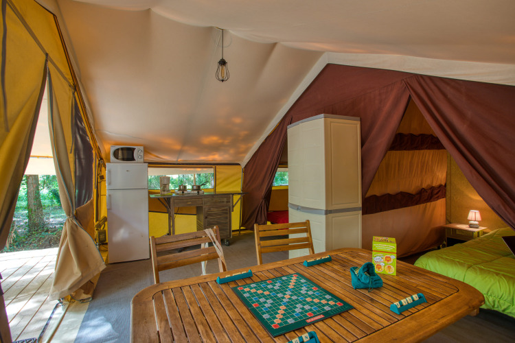 Interior of Tente Safari Confort at Flower Camping La Sagne, France, featuring kitchen and game table.