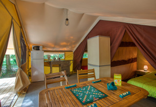 Interieur van Tente Safari Confort bij Flower Camping La Sagne, Frankrijk, met keuken en speeltafel.