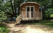 Roulotte Standard-Lodge bei Flower Camping La Sagne in Frankreich, mitten im Grünen und mit Terrasse.