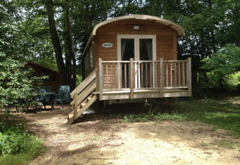 Roulotte Standard-lodge ved Flower Camping La Sagne i Frankrig, omgivet af træer og udendørs siddeplads.
