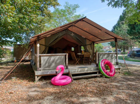 Safaritent Freeflower Confort met houten terras, tuinmeubilair en opblaasbare zwembadringen vooraan.