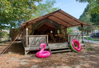 Safari-Zelt Freeflower Confort mit Holzveranda, Gartenmöbeln und aufblasbaren Schwimmringen vorne.