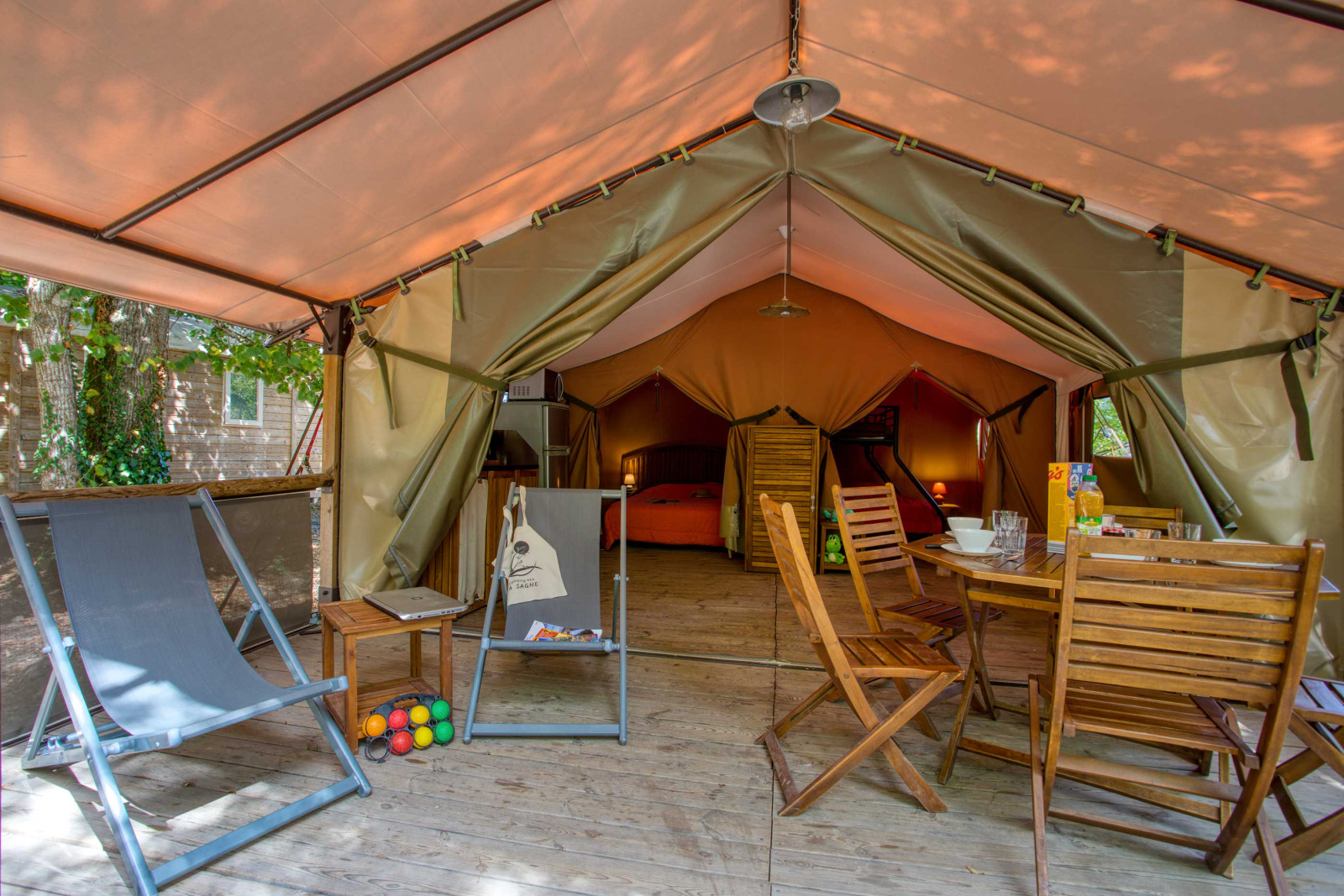Interieur van een Freeflower Confort safaritent bij Flower Camping La Sagne in Frankrijk, met houten meubilair.