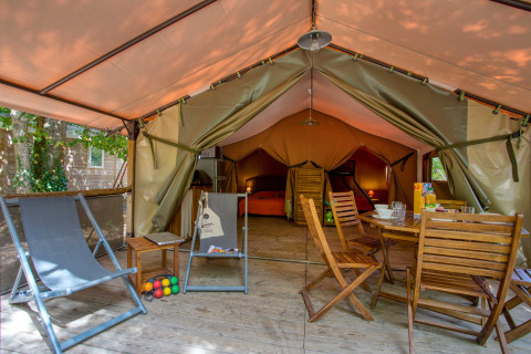Binnenzicht van een Freeflower Confort safaritent bij Flower Camping La Sagne in Frankrijk met houten stoelen.
