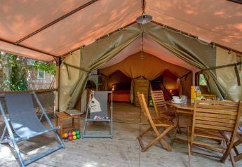 Innenansicht eines komfortablen Freeflower Safari-Zeltes im Flower Camping La Sagne in Frankreich mit Holzstühlen.