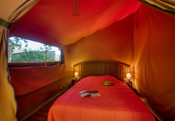 Interno della tenda safari Freeflower Confort al Flower Camping La Sagne in Francia con letto matrimoniale.
