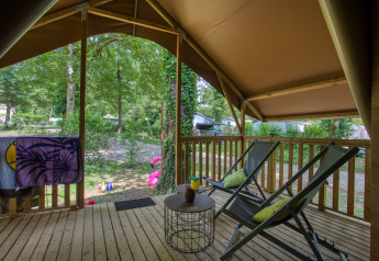 Vista dal terrazzo di una tenda safari con due sedie e tavolino al Flower Camping La Sagne, Francia.