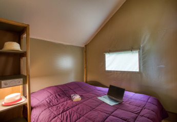 Interno camera da letto in tenda safari Wood Lodge Confort al Flower Camping La Sagne in Francia.