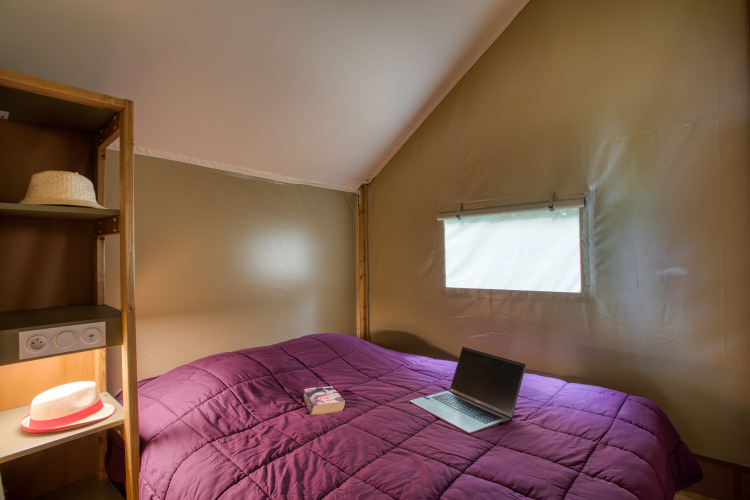 Interior de dormitorio de una tienda safari Wood Lodge Confort en Flower Camping La Sagne, Francia.
