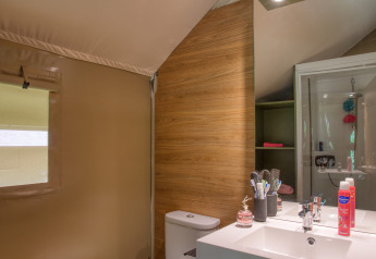 Bagno nella tenda safari Wood Lodge Confort al Flower Camping La Sagne, con wc e lavandino moderno.