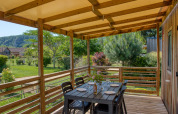 Überdachte Holzterrasse mit Esstisch an der Stacaravan Campbell Premium, Flower Camping La Sagne, Frankreich.