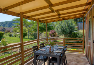 Terrasse en bois couverte avec table à manger au Stacaravan Campbell Premium, Flower Camping La Sagne, France.
