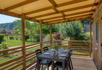Überdachte Holzterrasse mit Esstisch an der Stacaravan Campbell Premium, Flower Camping La Sagne, Frankreich.