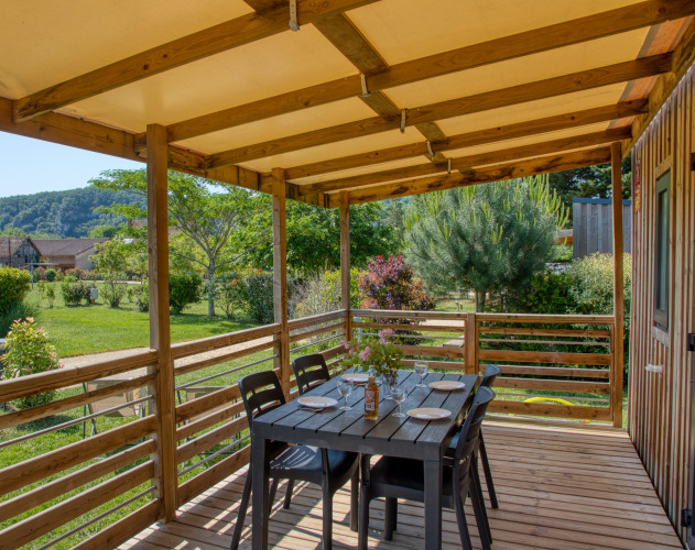 Træterrasse med spisebord ved Stacaravan Campbell Premium, Flower Camping La Sagne, omgivet af natur.