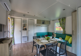 Interior of Stacaravan Campbell Premium lodge at Flower Camping La Sagne in France, showing dining zone.