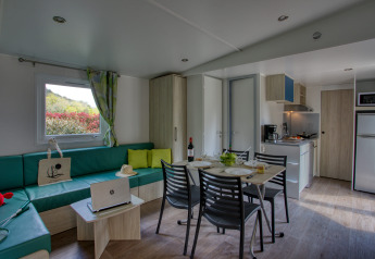 Interior view of a modern living and kitchen area in Stacaravan Campbell Premium at Flower Camping La Sagne.