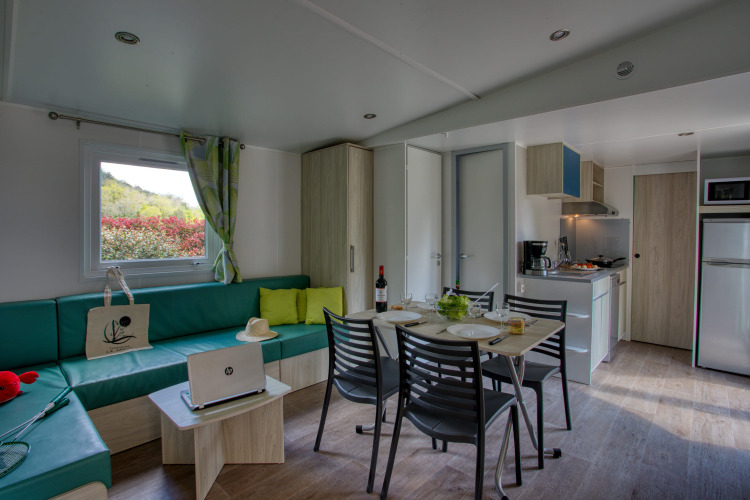 Vista interna di soggiorno e cucina moderni in Stacaravan Campbell Premium a Flower Camping La Sagne, Francia.