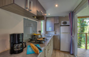 Cocina moderna de casa móvil con cafetera, pan y cocina en Stacaravan Cayuga Confort, Flower Camping La Sagne.