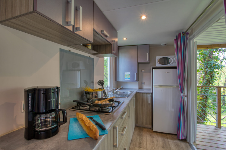Cuisine de mobil-home moderne avec cafetière, pain et cuisinière au Stacaravan Cayuga Confort en France.