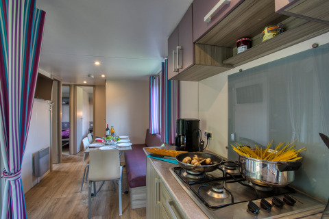Modern mobile home kitchen and dining area in Stacaravan Cayuga Confort at Flower Camping La Sagne, France.