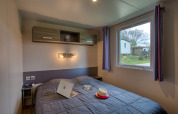Dormitorio en Stacaravan Cayuga Confort en Flower Camping La Sagne, Francia, con ventana al exterior.