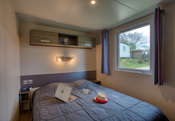 Camera da letto in Stacaravan Cayuga Confort presso Flower Camping La Sagne in Francia, con vista esterna.