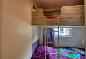 Værelse i mobilhome Stacaravan Cayuga Confort med køjesenge og spil på Flower Camping La Sagne, Frankrig.