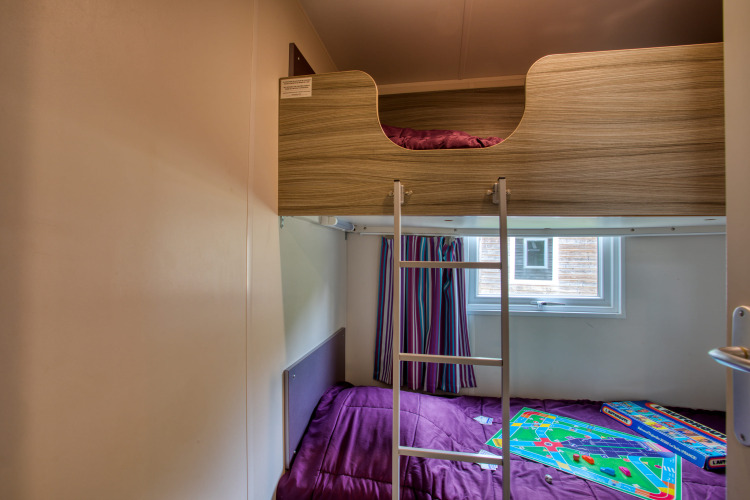 Chambre du mobil-home Stacaravan Cayuga Confort avec lits superposés et jeux au Flower Camping La Sagne, France.