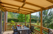 Überdachte Terrasse mit Esstisch und Stühlen an der Stacaravan Arlequin Premium im Flower Camping La Sagne, Frankreich.