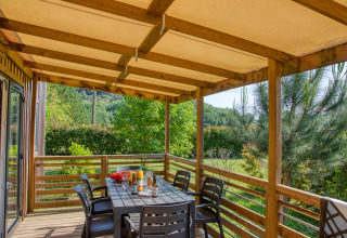 Covered terrace with dining table and chairs at Stacaravan Arlequin Premium, Flower Camping La Sagne, France.