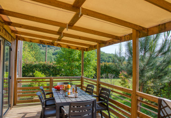 Überdachte Terrasse mit Esstisch und Stühlen an der Stacaravan Arlequin Premium im Flower Camping La Sagne, Frankreich.