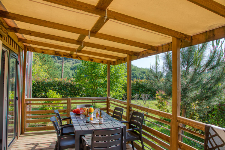 Overdekt terras met eettafel en stoelen bij Stacaravan Arlequin Premium op Flower Camping La Sagne, Frankrijk.