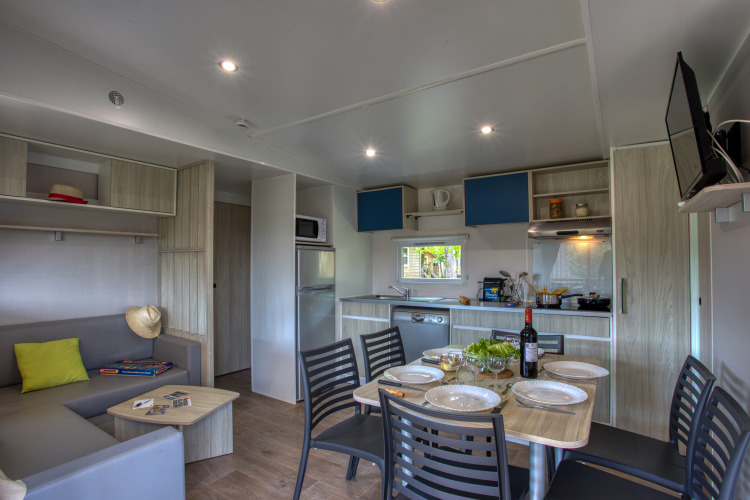 Moderne lodge woonkamer en keuken in Stacaravan Arlequin Premium bij Flower Camping La Sagne, Frankrijk.