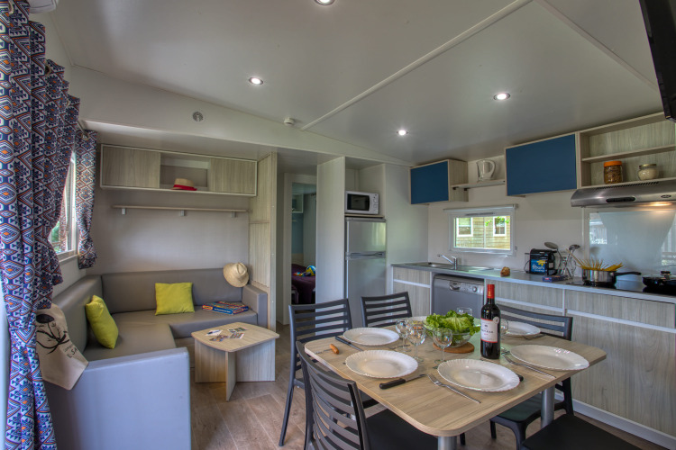 Moderne woonkamer en keuken in Stacaravan Arlequin Premium bij Flower Camping La Sagne in Frankrijk.