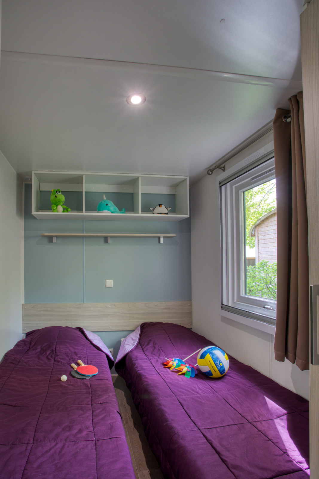 Knusse kamer in Stacaravan Arlequin Premium, Flower Camping La Sagne, met twee bedden en speelgoed.
