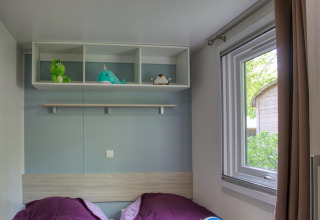 Chambre confortable au Stacaravan Arlequin Premium, Flower Camping La Sagne, avec deux lits et des jouets.