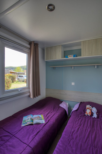 Twee eenpersoonsbedden met paarse dekens in de Stacaravan Arlequin Premium op Flower Camping La Sagne.