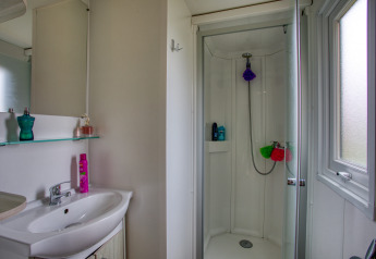 Baño moderno con ducha, lavabo y ventana en Stacaravan Arlequin Premium en Flower Camping La Sagne, Francia.