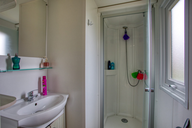 Baño moderno con ducha, lavabo y ventana en Stacaravan Arlequin Premium en Flower Camping La Sagne, Francia.