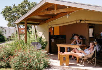 Due persone si rilassano sotto la tettoia in una tenda safari Ecolodge Cotton Toilée CONFORT.