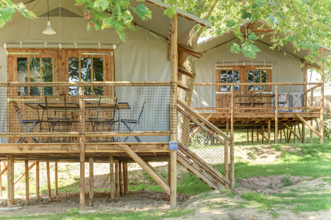 Elevated wooden cabins with netted decks under trees at Hut Lodge CONFORT, Flower Camping Le Conleau, France.