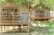 Elevated wooden cabins with netted decks under trees at Hut Lodge CONFORT, Flower Camping Le Conleau, France.