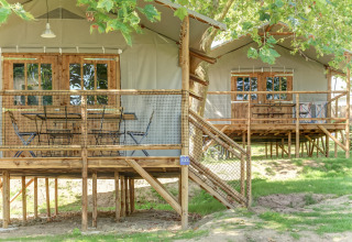 Elevated wooden cabins with netted decks under trees at Hut Lodge CONFORT, Flower Camping Le Conleau, France.