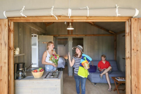 Indoor scene of people enjoying a cozy cabin at Hut Lodge CONFORT, Flower Camping Le Conleau in France.